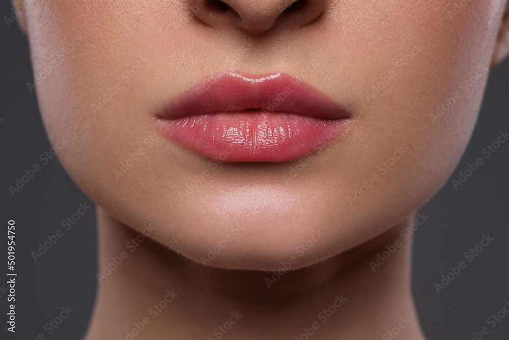 Young woman with beautiful lips on grey background, closeup