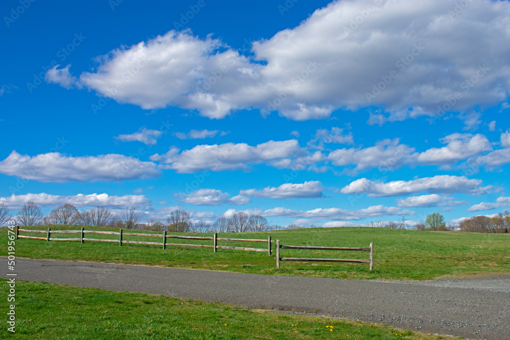 A sunny spring day with beautiful cumulus clouds over a fenced field at Big Brook Park, Marlboro, New Jersey -05