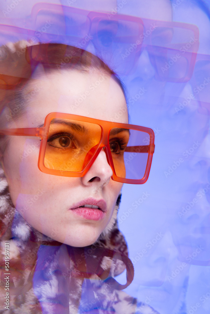 Art portrait, a woman with pink lips in orange glasses and a leopard hoodie on a blue background
