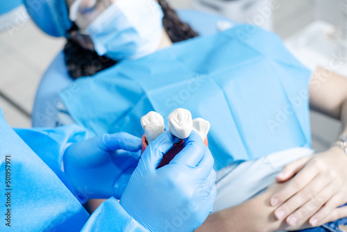hands with glove showing a model of a dental implant.