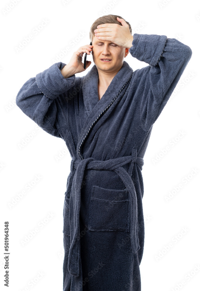 portrait of a man in a gray terry bathrobe. the man is sick and talking on the phone, calling an ambulance, a doctor. quarantine. isolated. portrait of a man in a gray terry bathrobe. the man is sick and talking on the phone, calling an ambulance, a doctor. quarantine. isolated.