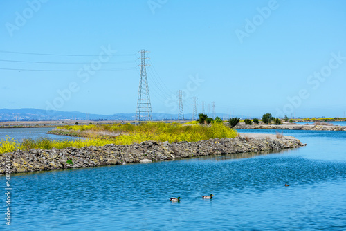 High voltage electricity power lines and transmission towers crossing the ponds, marshes and levees in San Francisco Bay, California photo