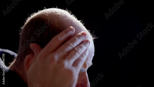 SLOW MOTION BACKLIT - A bald man inspects his pattern hair loss photo
