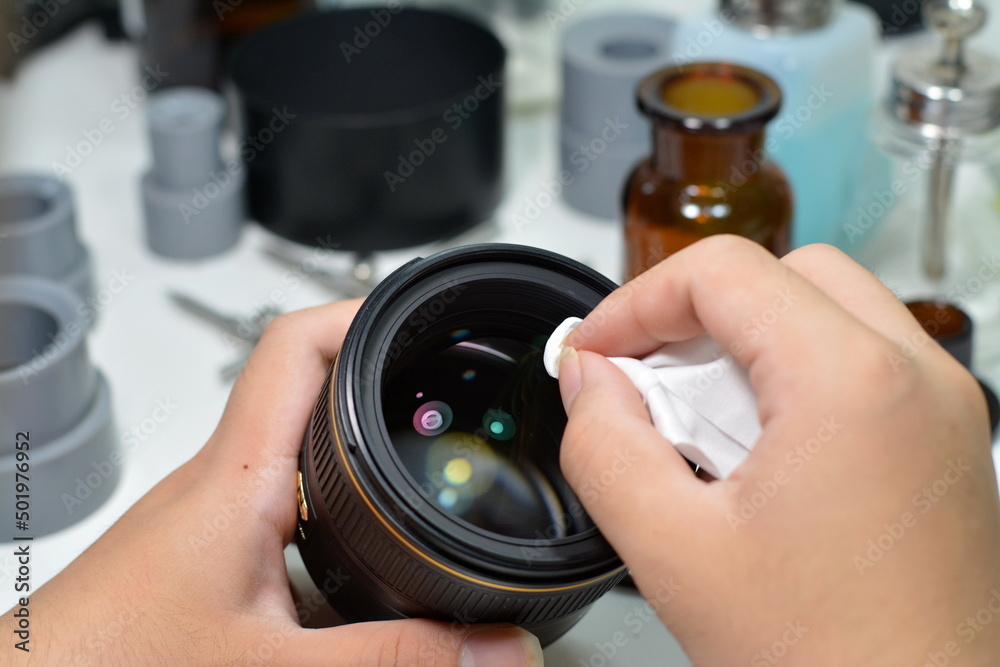 Photography equipment maintenance service Close-up of a technician cleaning a camera lens with a wet wipe.