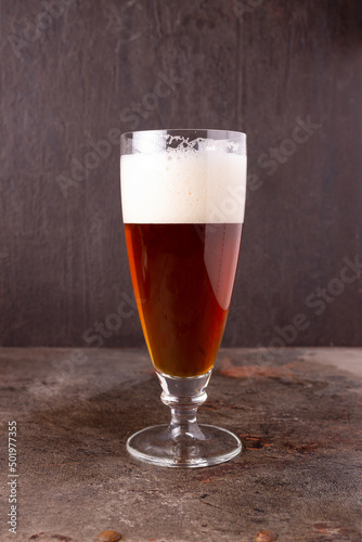 a glass of beer stands on a rusty iron sheet, side view