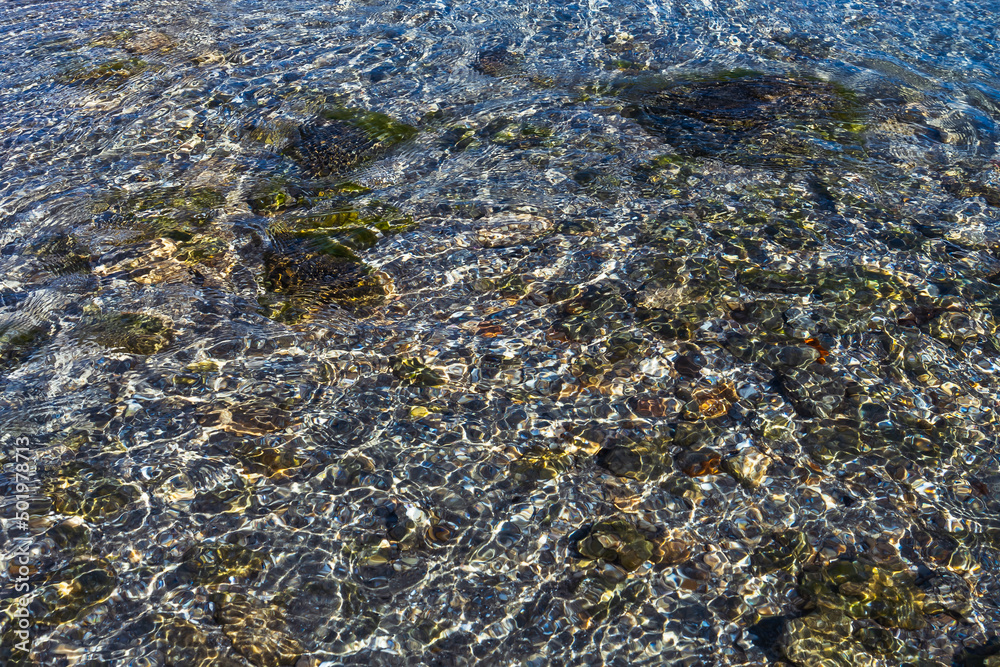 Multi-colored stones on a rocky beach at the bottom of the sea in the surf Multi-colored stones on a rocky beach at the bottom of the sea in the surf