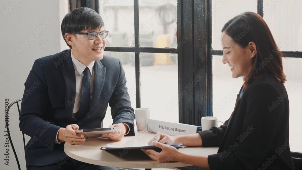 Happy two Asian young businessman and woman shaking hands greeting before meeting or negotiation with digital tablet sitting on desk cafe, Businesspeople discussion planning and smile lunch