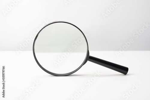 Magnifying glass black color on white table. Research, searching or investigating something. front view Magnifying glass