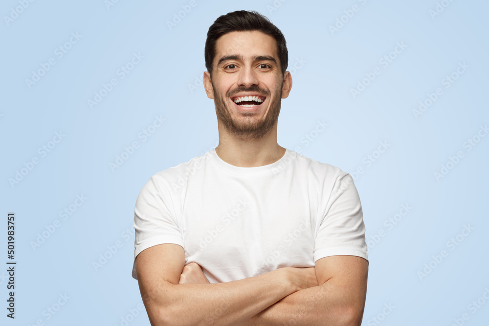 Young attractive European man with arms crossed shows opened friendly smile Young attractive European man with arms crossed shows opened friendly smile