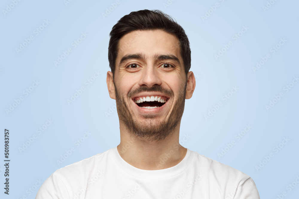 Attractive handsome unshaven young man in white t-shirt laughs out loud Attractive handsome unshaven young man in white t-shirt laughs out loud