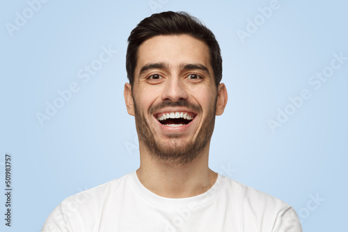 Attractive handsome unshaven young man in white t-shirt laughs out loud