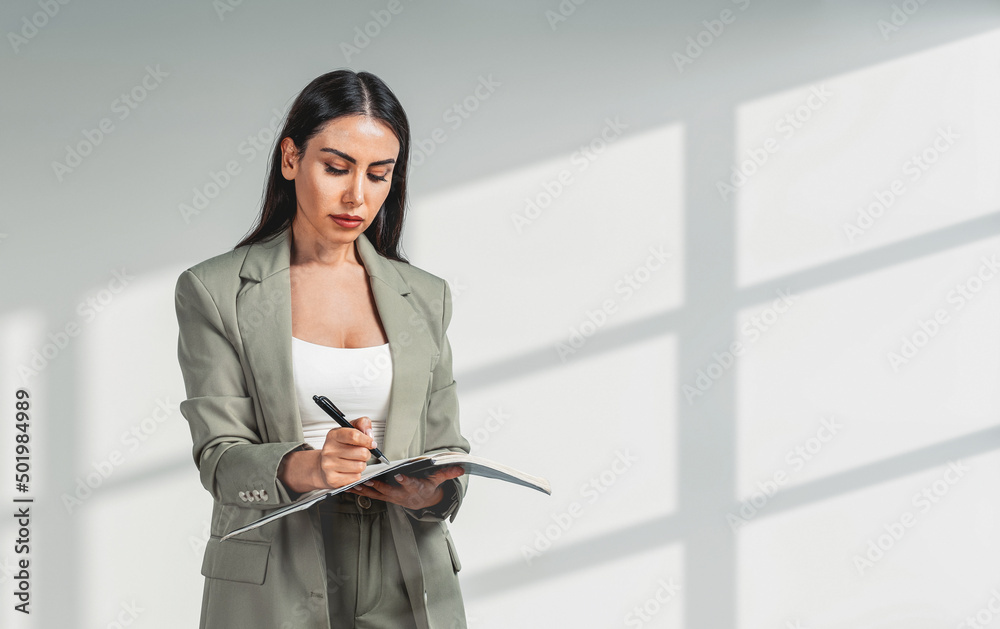 Office woman take note with notebook in hands standing on light background Office woman take note with notebook in hands standing on light background