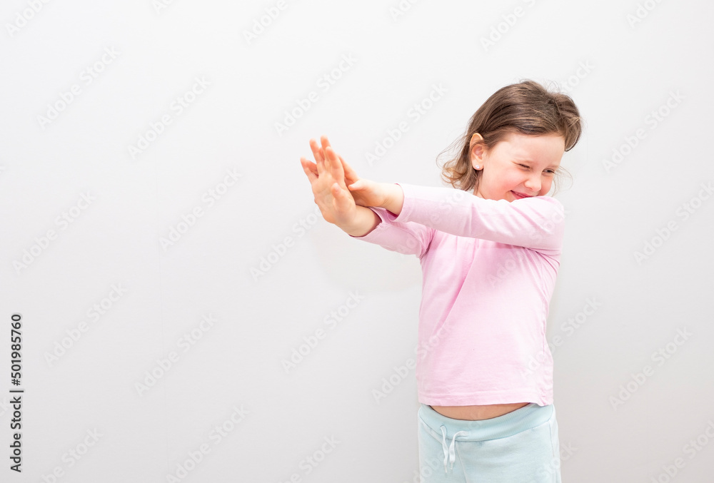 Child, Caucasian 6 years old, in a pink coat on a gray background. The child is stressed, shows a stop gesture with his hands, he is not happy. Child, Caucasian 6 years old, in a pink coat on a gray background. The child is stressed, shows a stop gesture with his hands, he is not happy.