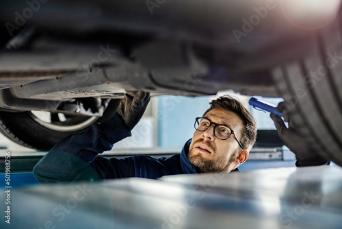 A car service worker looking under the car and trying to find issue.