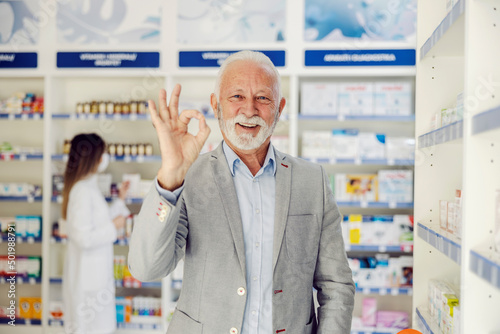 A senior man showing okay gesture at pharmacy. photo