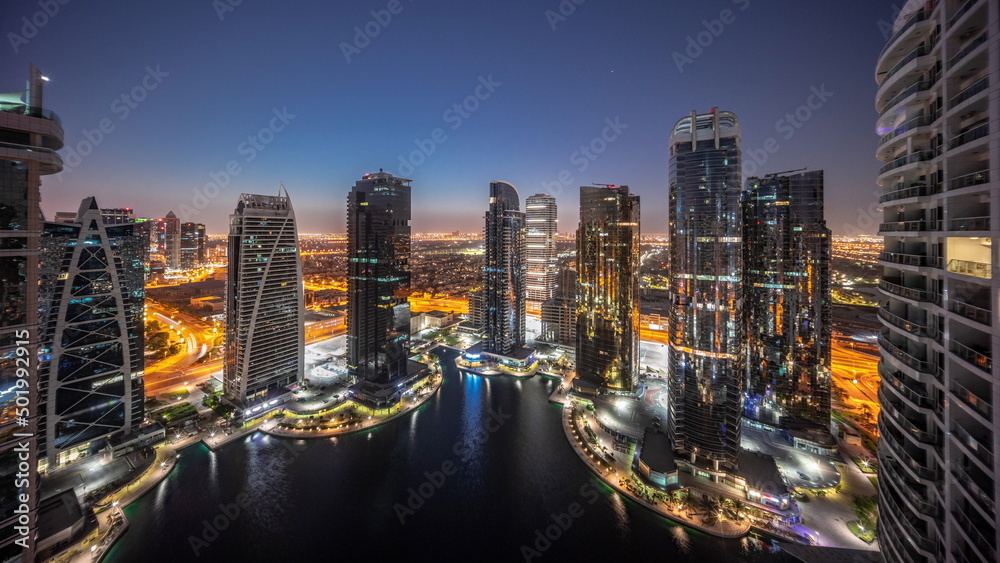 Tall residential buildings at JLT aerial night to day timelapse, part of the Dubai multi commodities centre mixed-use district.
