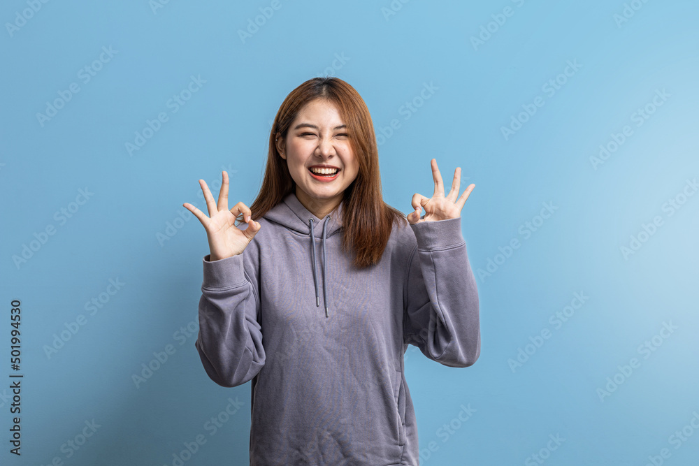 Portrait of beautiful Asian woman doing cheerful pose on isolated blue background, portrait concept used for advertisement and signage, isolated over blue background, copy space. Portrait of beautiful Asian woman doing cheerful pose on isolated blue background, portrait concept used for advertisement and signage, isolated over blue background, copy space.