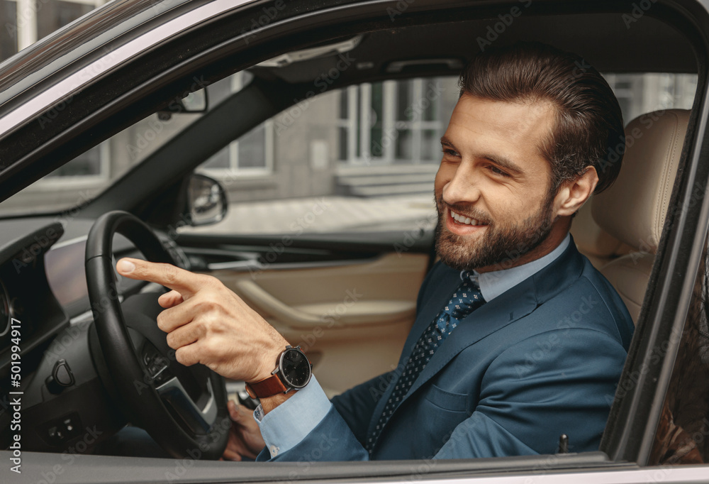 Adorable confident male in formal clothes gesturing in the automobile