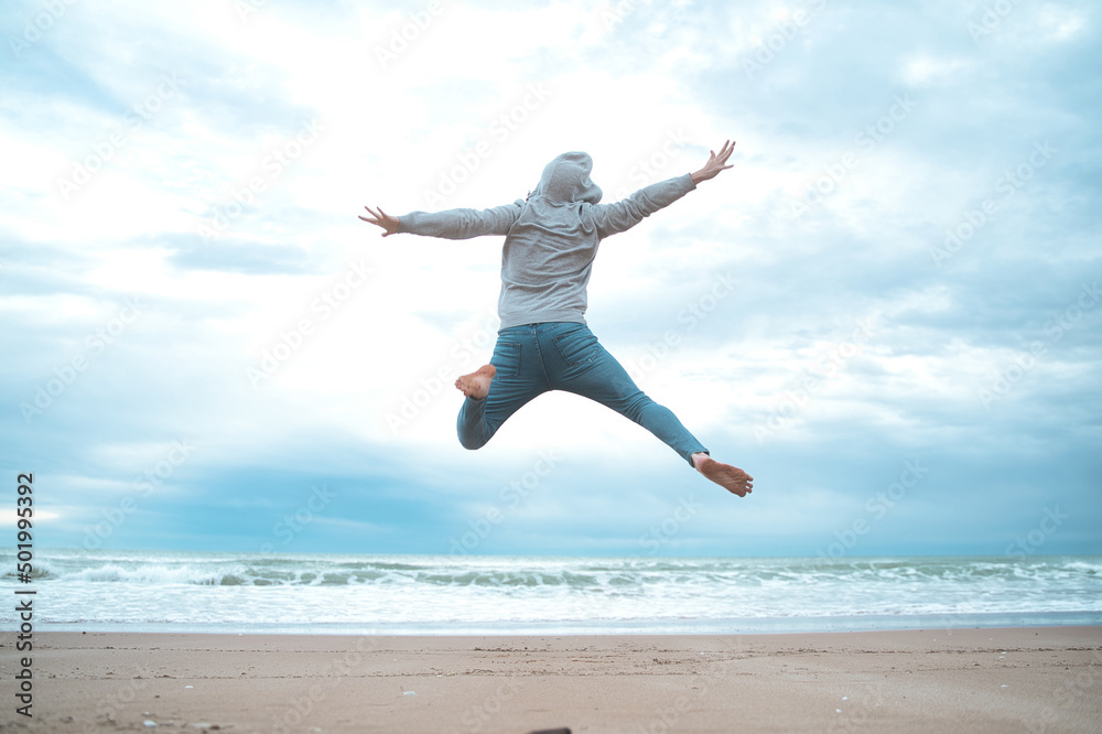 Feel good and freedom concept. Copy space of happy man jumping on beach. 