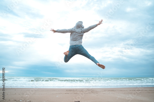 Feel good and freedom concept. Copy space of happy man jumping on beach. 