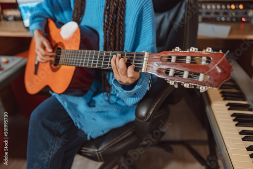 Focus on the hands of a guitarist keeping fingers on the strings while playing the guitar in the sound recording studio