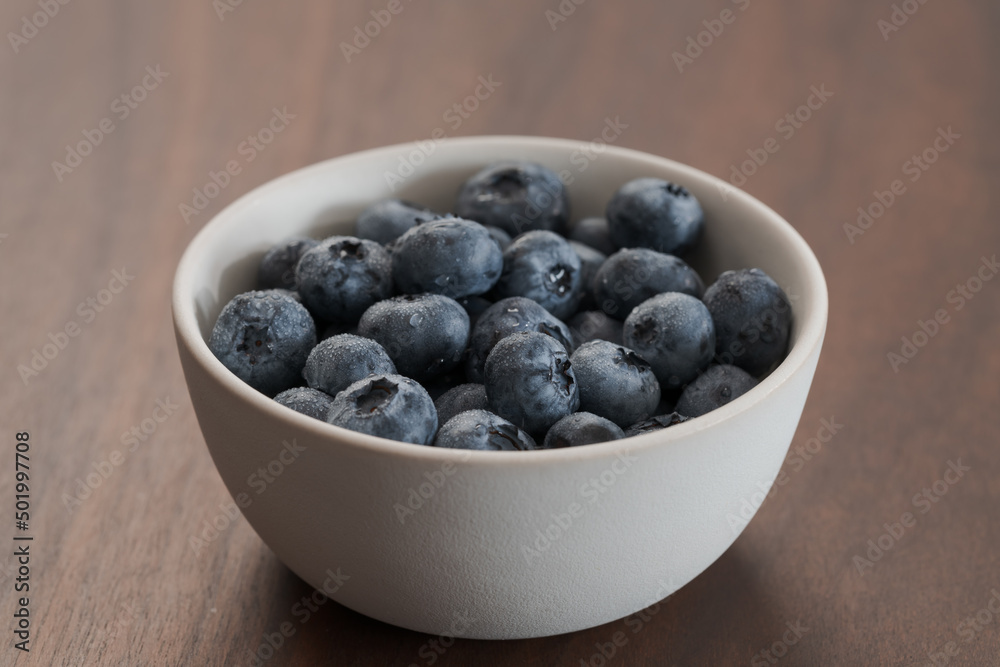 Fresh washed blueberries in white bowl on walnut table Fresh washed blueberries in white bowl on walnut table