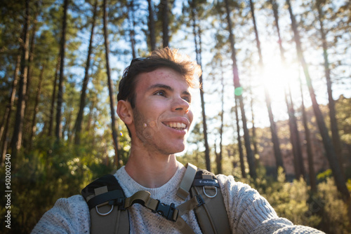 Young hiker man taking selfie portrait in a pine tree forest - Happy guy smiling - Hiking, sport, travel and well-being concept