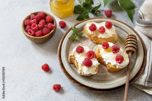 Healthy summer breakfast with sweet sandwiches with ricotta, raspberries and honey on a stone table. Copy space.