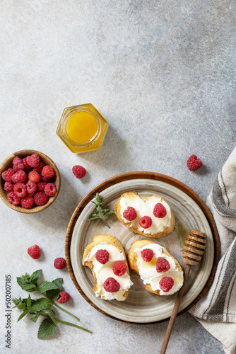 Healthy summer breakfast with sweet sandwiches with ricotta, raspberries and honey on a stone table. Top view flat lay. Copy space.