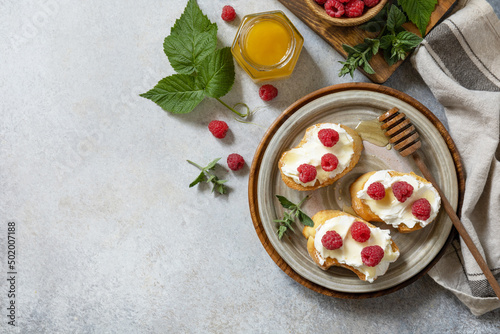 Healthy summer breakfast with sweet sandwiches with ricotta, raspberries and honey on a stone table. Top view flat lay. Copy space.