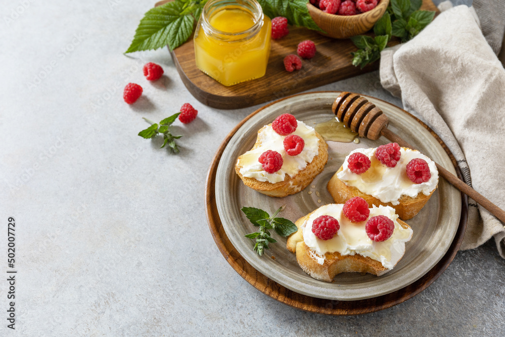 Healthy summer breakfast with sweet sandwiches with ricotta, raspberries and honey on a stone table. Copy space. Healthy summer breakfast with sweet sandwiches with ricotta, raspberries and honey on a stone table. Copy space.
