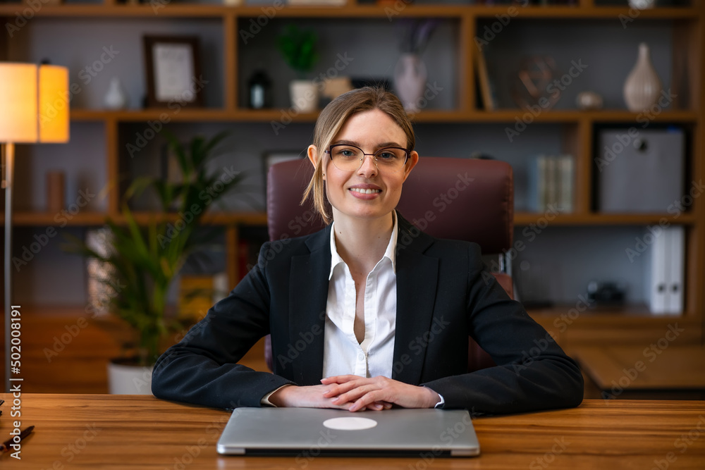 Happy portrait of successful confident business woman sitting at the table in the office looks at the camera and smiling in friendly Happy portrait of successful confident business woman sitting at the table in the office looks at the camera and smiling in friendly