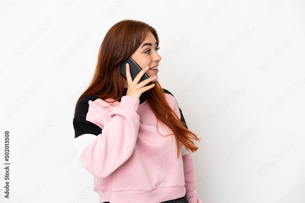 Young redhead woman isolated on white background keeping a conversation with the mobile phone with someone Young redhead woman isolated on white background keeping a conversation with the mobile phone with someone