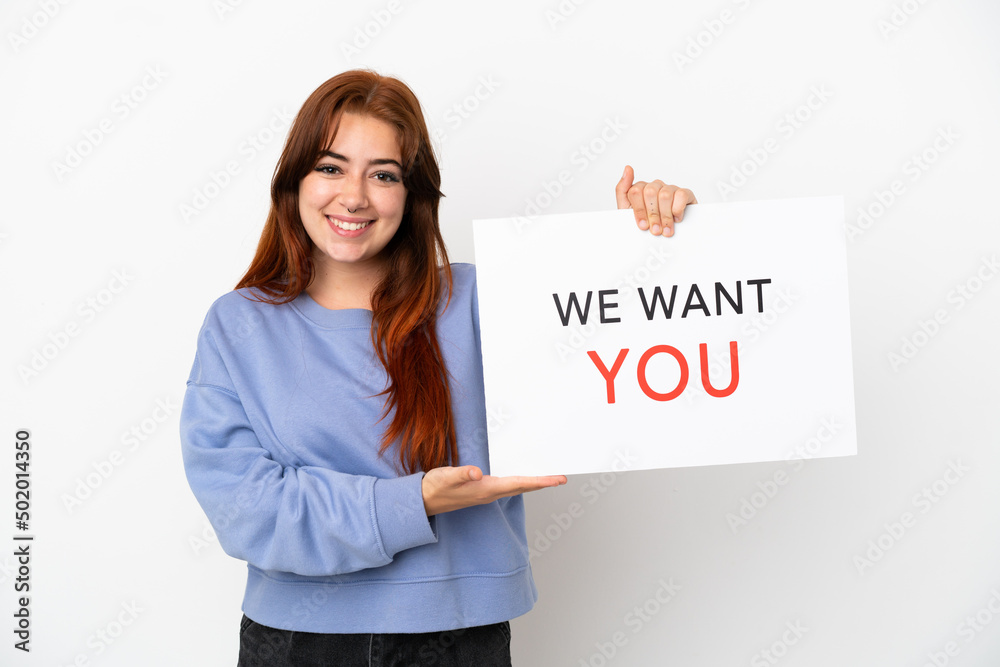 Young redhead woman isolated on white background holding We Want You board with happy expression Young redhead woman isolated on white background holding We Want You board with happy expression