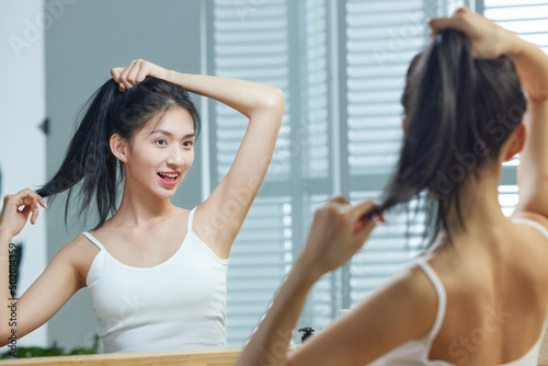 A beautiful young woman look into a mirror whilst combing your hair photo