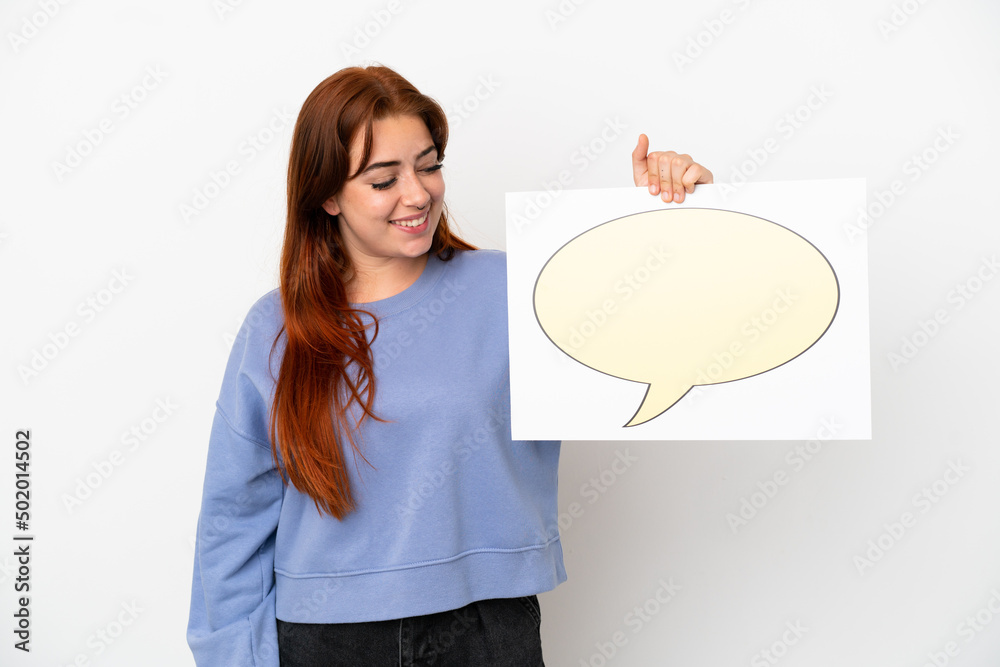 Young redhead woman isolated on white background holding a placard with speech bubble icon Young redhead woman isolated on white background holding a placard with speech bubble icon