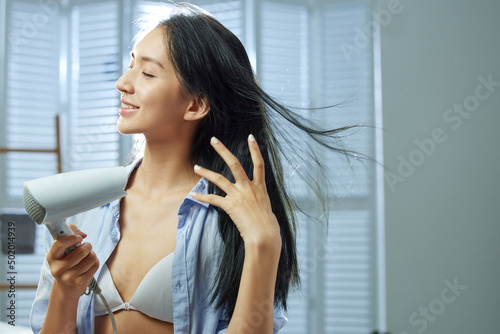 A beautiful young woman use hair dryer photo