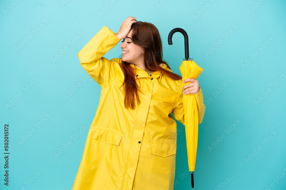 Redhead woman holding an umbrella isolated on blue background has realized something and intending the solution Redhead woman holding an umbrella isolated on blue background has realized something and intending the solution