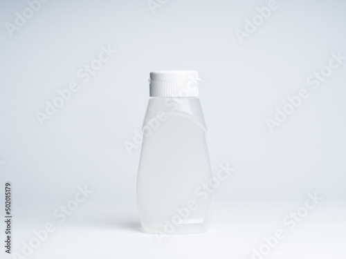 A white matte plastic bottle curved shape with dispenser for sauces isolated on white background, front view with empty space on it and no label, photo studio shot.