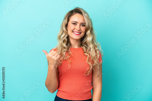Young Brazilian woman isolated on blue background pointing to the side to present a product © luismolinero