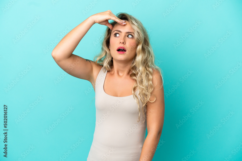 Obraz premium Young Brazilian woman isolated on blue background doing surprise gesture while looking to the side