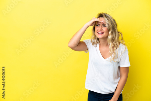 Young Brazilian woman isolated on yellow background looking far away with hand to look something