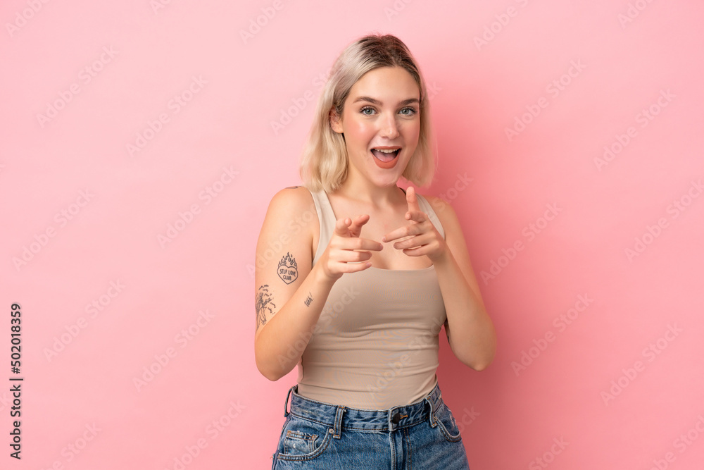 Young caucasian woman isolated on pink background surprised and pointing front Young caucasian woman isolated on pink background surprised and pointing front