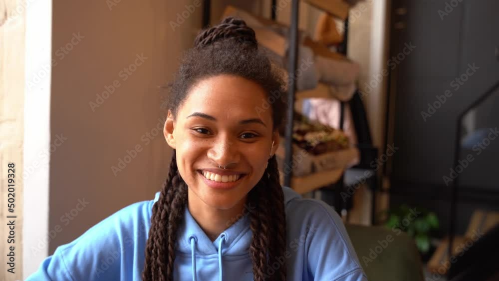 Beautiful cheerful stylish woman smiling in cozy cafe. Pretty young female in blue hoodie. Portrait Beautiful cheerful stylish woman smiling in cozy cafe. Pretty young female in blue hoodie. Portrait