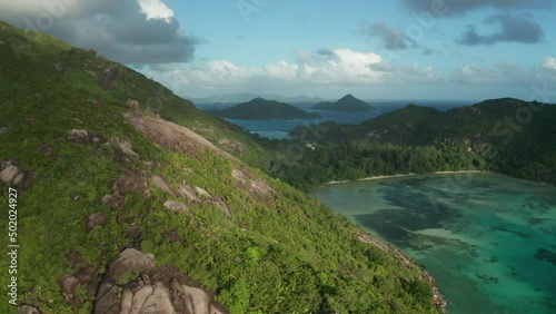 Aerial dolly over slope of hilly granite mountain of coast Ternay bay