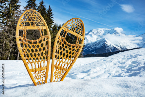 Pair of the wooden snowshoes in snow over mountain peaks
