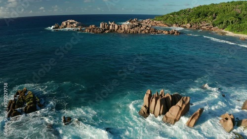 Aerial dolly and lift up over shore and gulf Grand l'Anse, La Digue