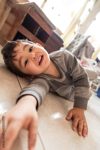 boy on the floor of his home smiling at the camera