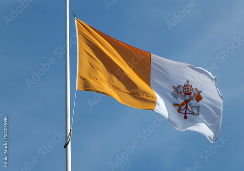 vatican state flag flying against a bright blue sunlit sky photo