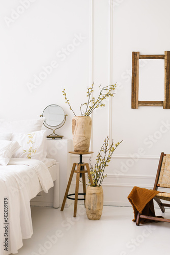 A cozy bed and vases with spring branches. Natural Bedroom decor